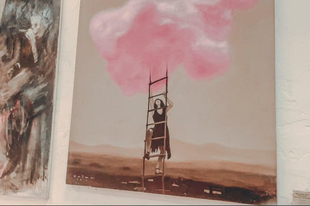 A contemporary painting of a woman climbing a ladder toward pink cloud, inside Pinto Art Museum, Antipolo, Rizal