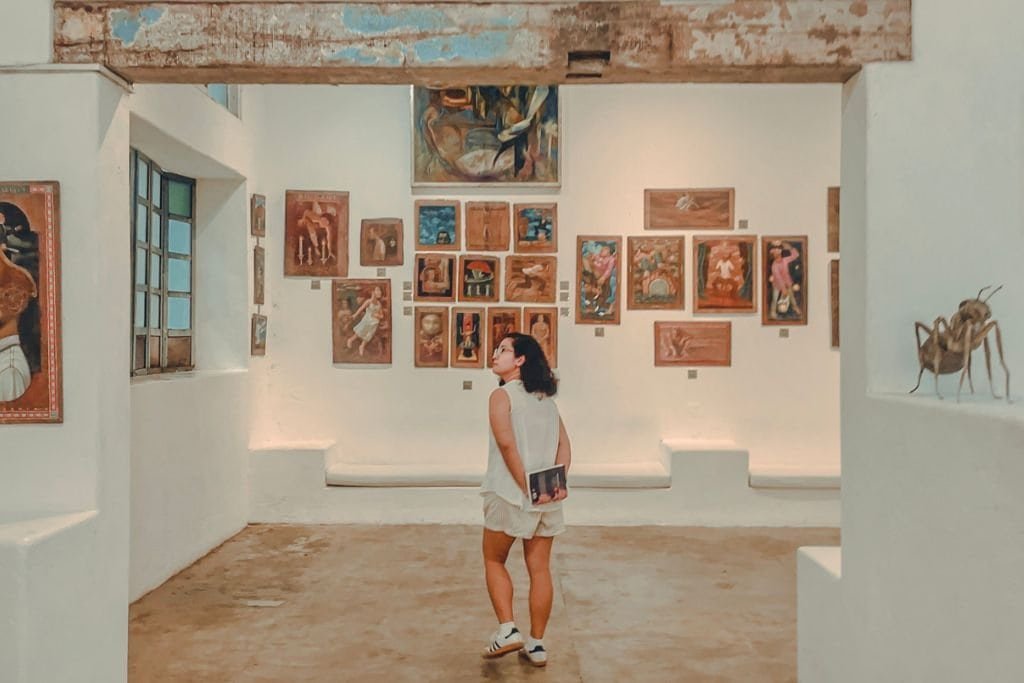 A woman standing in a gallery, looking at art, taking time to engage in Filipino contemporary art at Pinto Art Museum in Antipolo