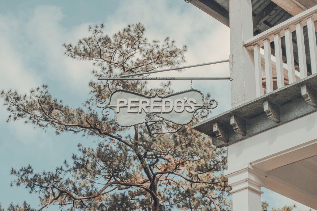 Signage of Peredo's Lodging House, backdropped by a tree