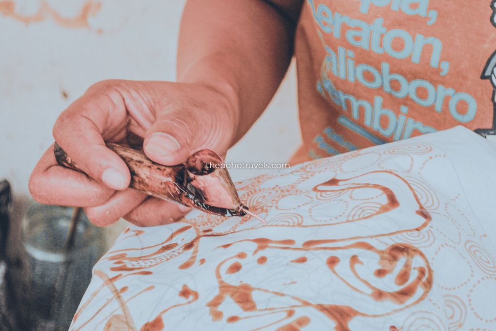 A local artisan painting a batik in Yogyakarta, Indonesia. Learning batik painting is one of the best things to do in Yogyakarta