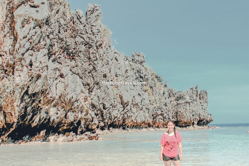 A lady in fuchsia pink top enjoying one of the pristine islands of El Nido, Palawan, one of the best things to do in El Nido