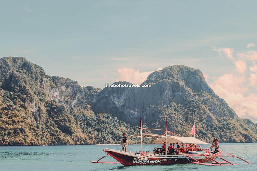 El Nido island hopping tour group while on a boat with the backdrop of gorgeous limestone formations