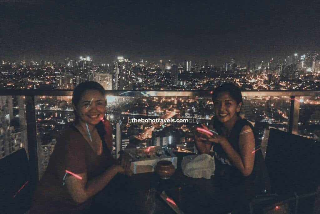 friends having drinks at a Makati rooftop bar, with a view of the skyline