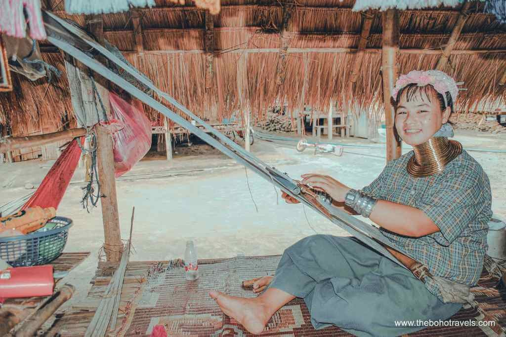 A Karieng woman weaving at a traditional loom at a Kayan village near the Golden Triangle, visited on a Chiang Rai day trip from Chiang Mai